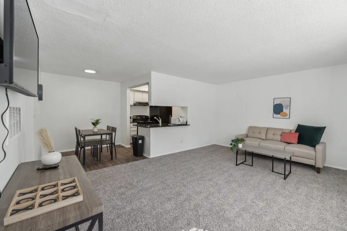 This image shows a cohesive space where the sofa, dining table, kitchen, and wall art are all visible together, creating a sense of flow and easy living. The furnishings are modern and inviting, and the layout is practical for both relaxing and entertaining.