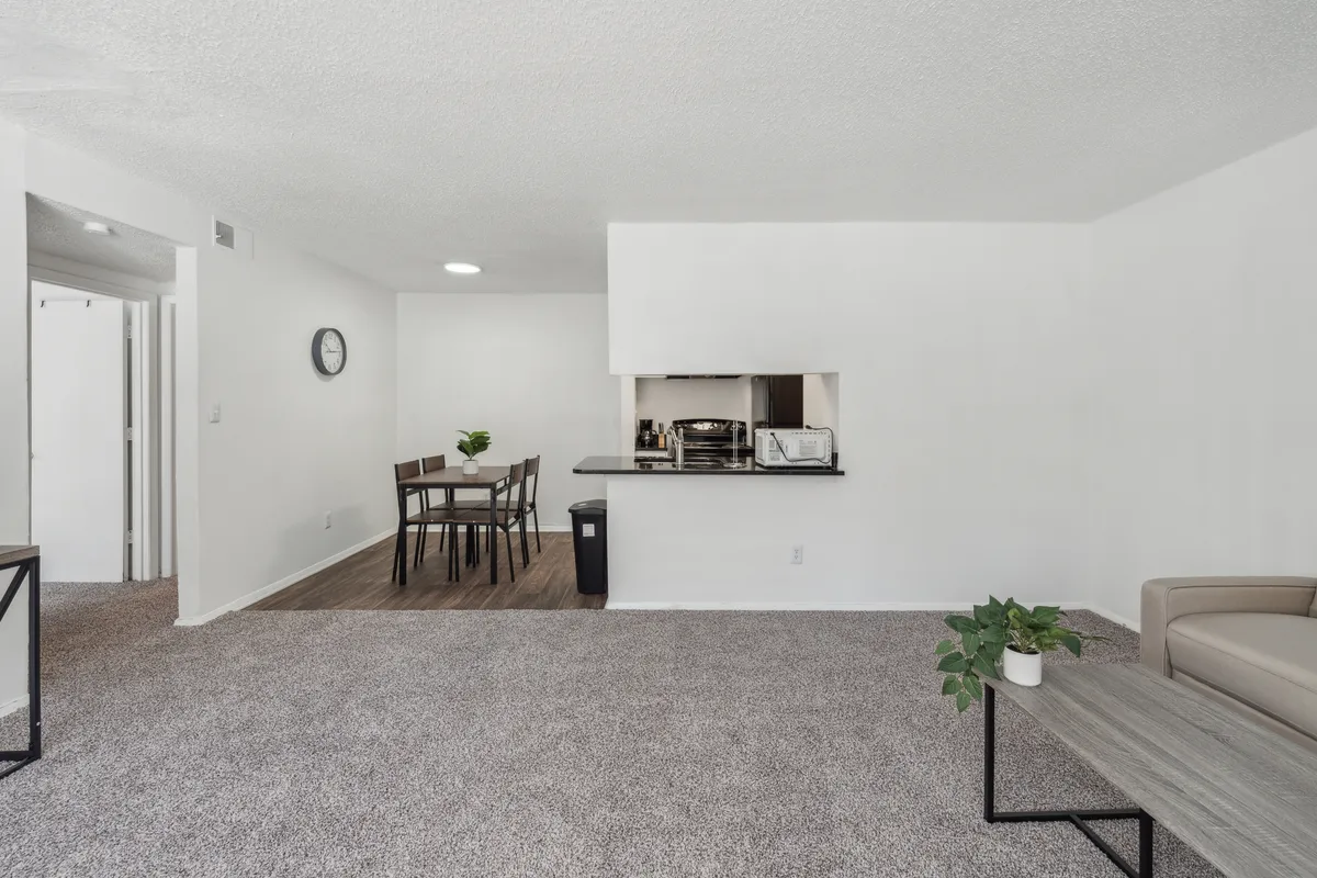 This image presents a welcoming seating area with a dining table and a kitchen pass-through, capturing a cozy yet social interior space perfect for small gatherings or intimate meals. The scene suggests possibilities for relaxed evenings and shared experiences before or after exploring the city's cultural attractions.